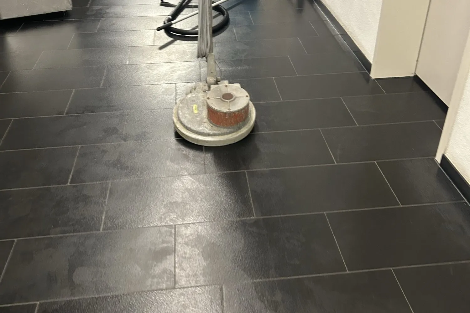 Flur mit dunklen Fliesen während der Grundreinigung mit der Einscheibenmaschine